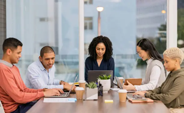 A diverse group of interns collaborating around a table, each with a laptop, engaged in a Google internship project.