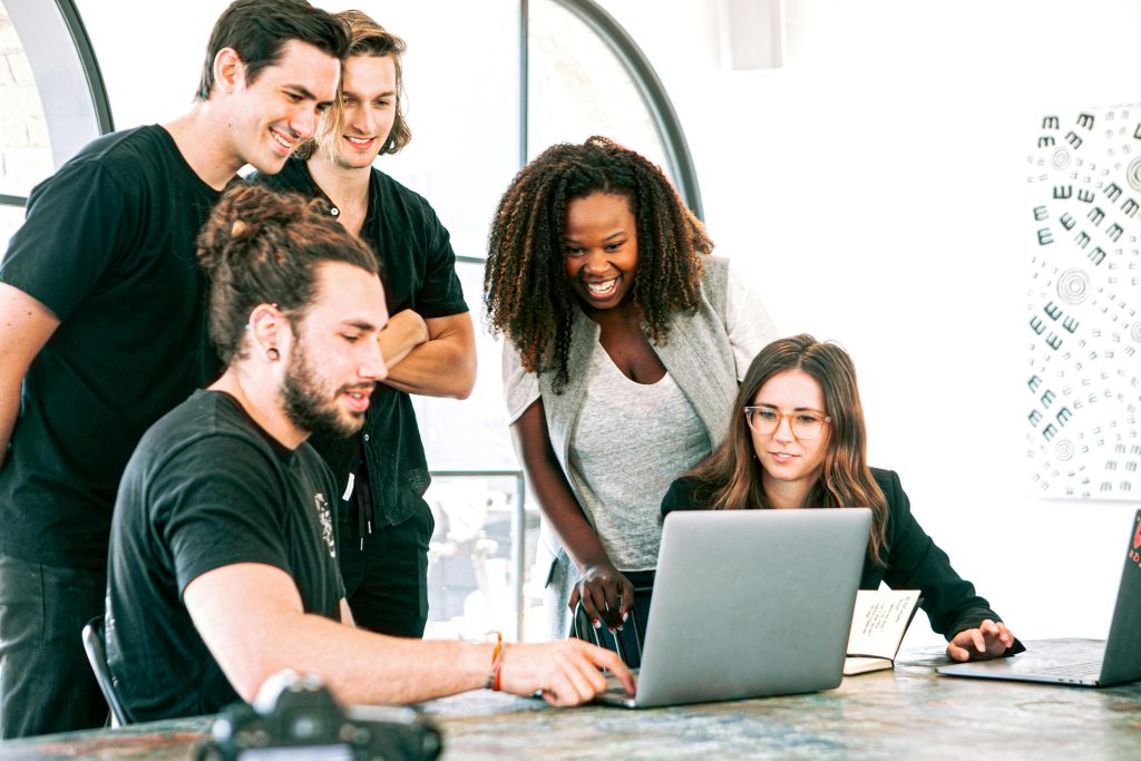 A team of interns engaged in discussion around a laptop, sharing ideas for their Google internship.