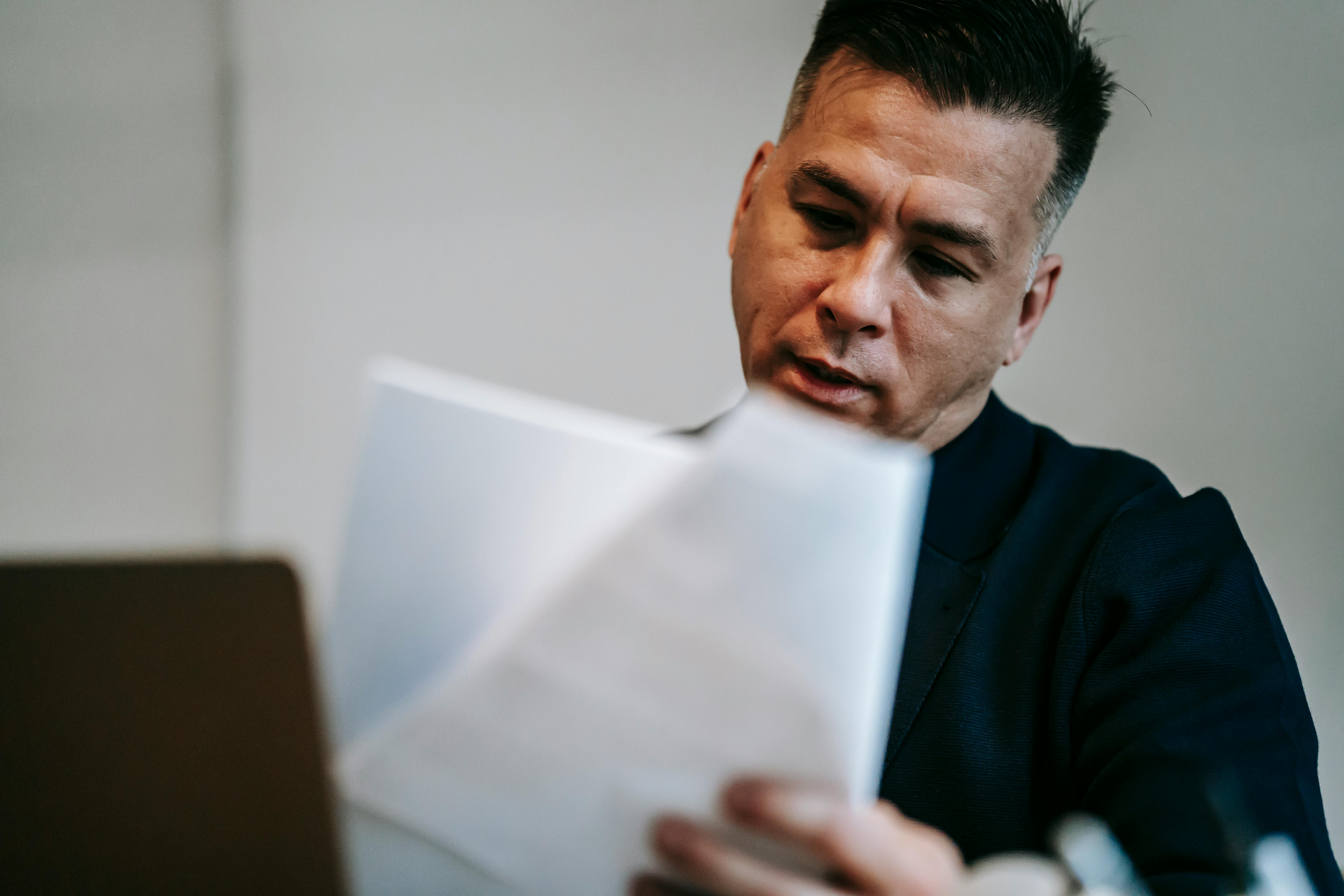A man reviews his Curriculum Vitae on a laptop, focused on the document displayed on the screen.